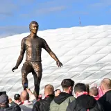 Pomnik piłkarza z Monachium przed stadionem. Fani robią zdjęcia.
