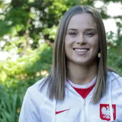Uśmiechnięta Ewa Pajor w stroju reprezentacyjnym, symbol polskiego sportu. Jej zarobki budzą zainteresowanie, ale talent i determinacja są bezcenne.
