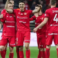 Piłkarze Widzewa Łódź w czerwonych strojach świętują na boisku.