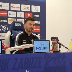 Trener Górnika Zabrze przed meczem z Rakowem Częstochowa. Na stole kabanosy, napoje i model samolotu.