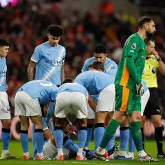 Piłkarze Manchesteru City w jasnoniebieskich strojach zbierają się w kółku na boisku. Skład drużyny w akcji.