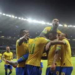 Piłkarze Brazylii świętują zwycięstwo nad Argentyną. Stadion wypełniony kibicami, nocne światła oświetlają murawę.