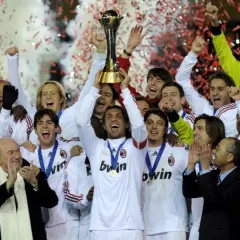 Piłkarze AC Milan świętują z pucharem, w tle konfetti i dym.