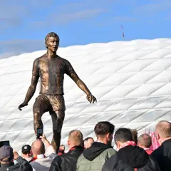 Pomnik piłkarza z Monachium przed stadionem. Fani robią zdjęcia.