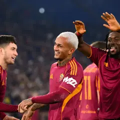 Piłkarze AS Roma świętują zwycięstwo nad Genoą CFC. Radość na twarzach zawodników, jeden z nich podnosi ręce w geście triumfu.