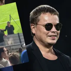 Właściciel Wisły Kraków w okularach przeciwsłonecznych, na tle fragmentu stadionu i kibiców.