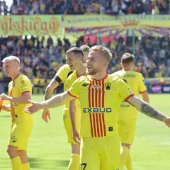Piłkarze Korony Kielce w żółtych strojach świętują po meczu z Jagiellonią Białystok. Radość na twarzach zawodników.