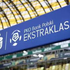 Niebieski baner z logo PKO Bank Polski Ekstraklasa na tle stadionu.