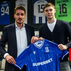 Dwóch mężczyzn prezentuje niebieską koszulkę Lecha Poznań. To kolejny z ekscytujących lech poznan transfery.