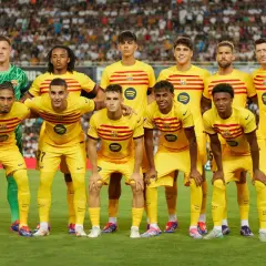 Drużyna FC Barcelona w żółtych strojach, z kapitanem na czele, pozuje do zdjęcia na tle trybun.