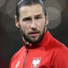 Piłkarz w czerwonej bluzie z orłem na piersi, w deszczu. Krychowiak gdzie gra? Na boisku, w barwach narodowych.