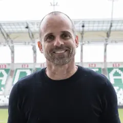 Uśmiechnięty trener Radomiaka na tle stadionu.