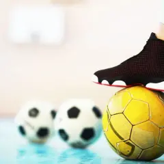 Stopa na żółtej piłce, w tle dwie białe. To może być początek przygody z futsalem.