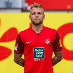 Piłkarz w czerwonej koszulce z herbem klubu, gdzie gra puchacz.