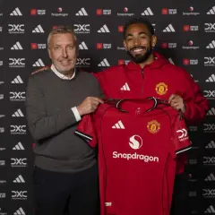 Dwóch mężczyzn prezentuje czerwoną koszulkę Manchester United. To ważny moment dla manchester united transfery.
