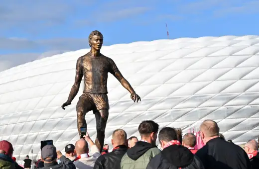 Pomnik piłkarza z Monachium przed stadionem. Fani robią zdjęcia.