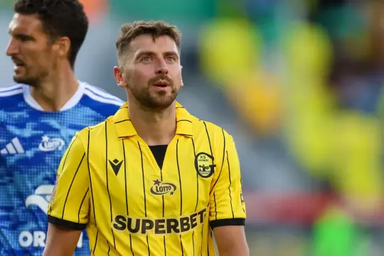 Piłkarz GKS Katowice w żółtej koszulce z czarnymi pasami, w tle inny zawodnik. Mecz: GKS Katowice – Wisła Płock.