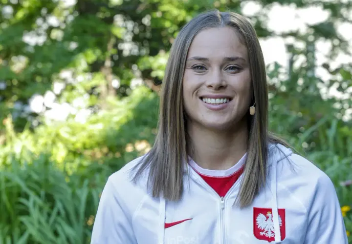 Uśmiechnięta Ewa Pajor w stroju reprezentacyjnym, symbol polskiego sportu. Jej zarobki budzą zainteresowanie, ale talent i determinacja są bezcenne.