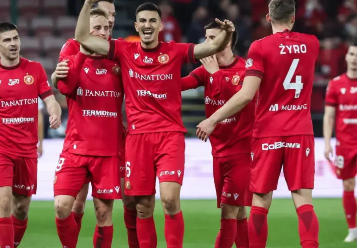 Piłkarze Widzewa Łódź w czerwonych strojach świętują na boisku.
