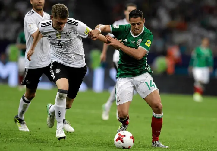 Piłkarze Niemiec i Meksyku walczą o piłkę na boisku. Intensywna gra podczas Pucharu Konfederacji UEFA.