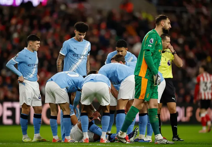 Piłkarze Manchesteru City w jasnoniebieskich strojach zbierają się w kółku na boisku. Skład drużyny w akcji.