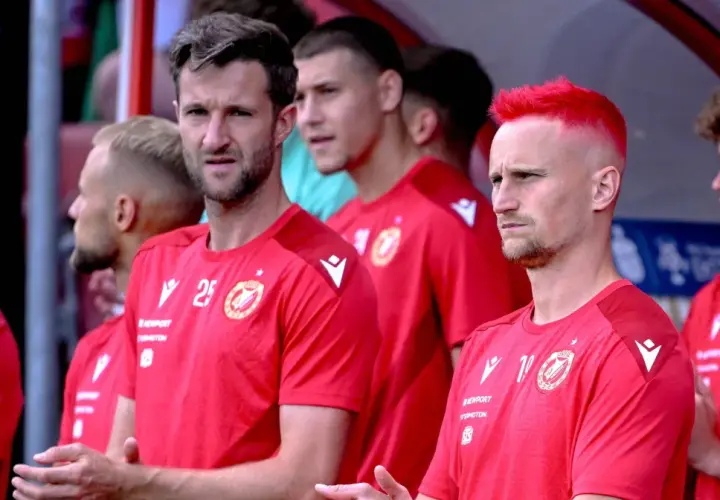 Piłkarze Widzewa Łódź w czerwonych koszulkach, jeden z nich ma jaskrawo-czerwone włosy.