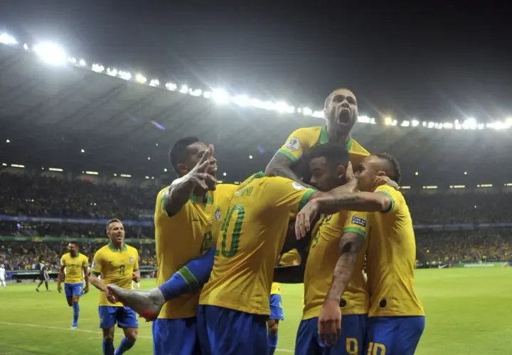 Piłkarze Brazylii świętują zwycięstwo nad Argentyną. Stadion wypełniony kibicami, nocne światła oświetlają murawę.