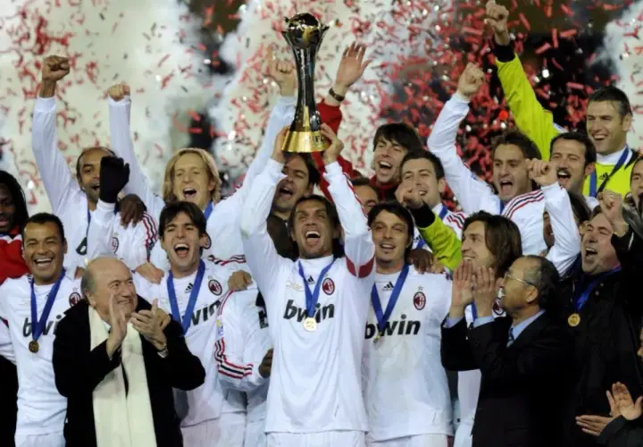 Piłkarze AC Milan świętują z pucharem, w tle konfetti i dym.