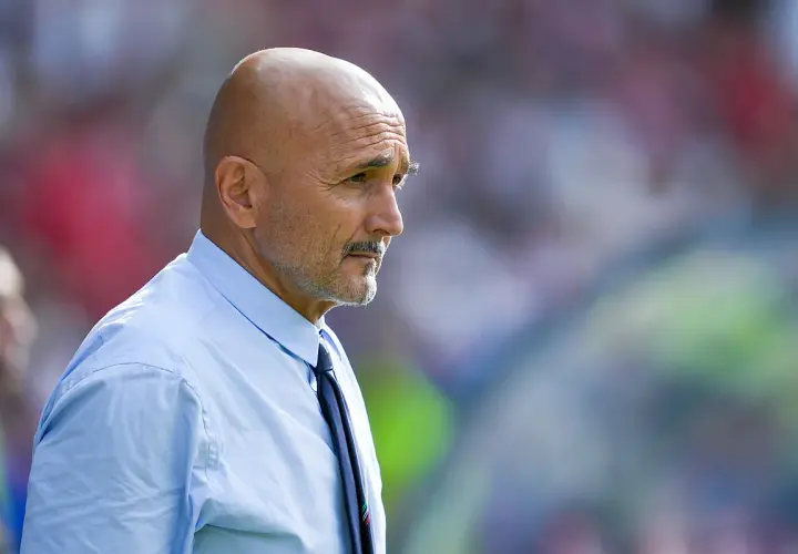 Łysy mężczyzna z wąsami, ubrany w błękitną koszulę i krawat, w skupieniu obserwuje boisko. To trener Juventusu.