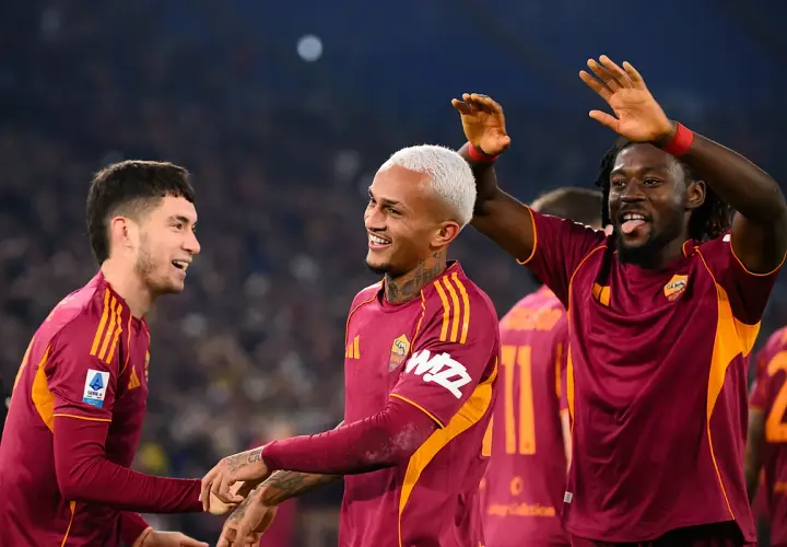 Piłkarze AS Roma świętują zwycięstwo nad Genoą CFC. Radość na twarzach zawodników, jeden z nich podnosi ręce w geście triumfu.