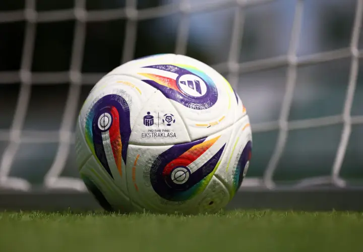 Piłka nożna PKO BP Ekstraklasa na trawie przed bramką.
