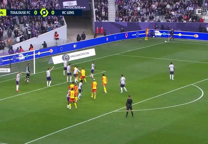 Mecz Toulouse FC - RC Lens. Piłkarze w białych i żółtych strojach szykują się do akcji pod bramką.