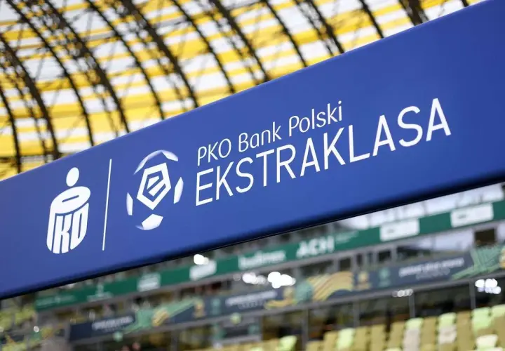 Niebieski baner z logo PKO Bank Polski Ekstraklasa na tle stadionu.