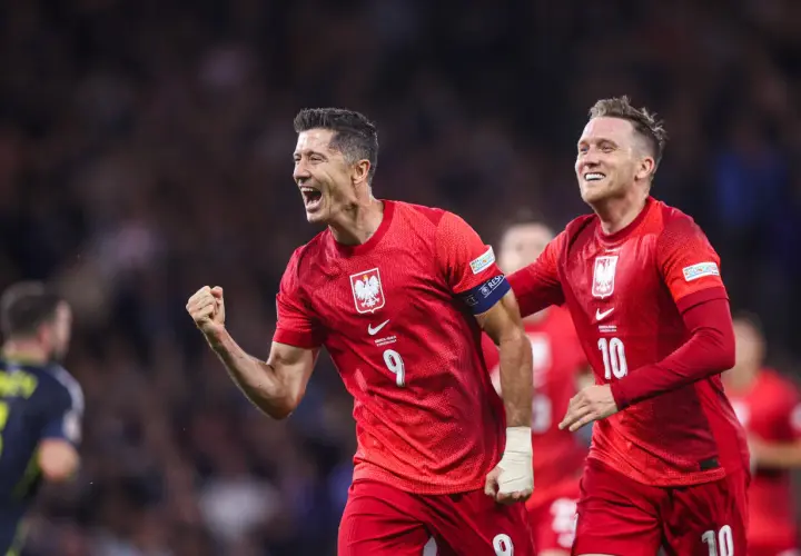 Dwóch radośnie świętujących byli piłkarze reprezentacji Polski w czerwonych strojach. Lewandowski z numerem 9 i Zieliński z numerem 10.