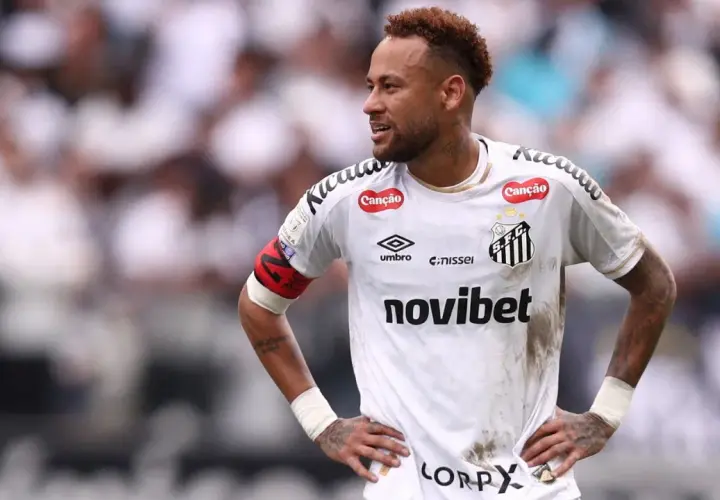Neymar w białej koszulce Santos FC, z opaską kapitana na ramieniu, na tle trybun.