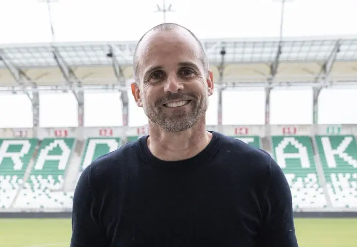 Uśmiechnięty trener Radomiaka na tle stadionu.