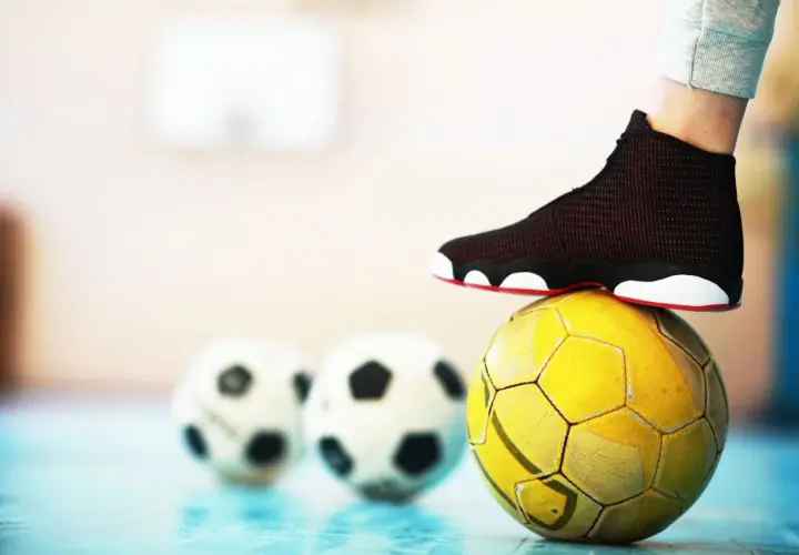 Stopa na żółtej piłce, w tle dwie białe. To może być początek przygody z futsalem.