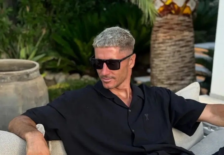 Robert Lewandowski w czarnej koszuli i okularach przeciwsłonecznych, relaksujący się w ogrodzie. Jego majątek robi wrażenie.