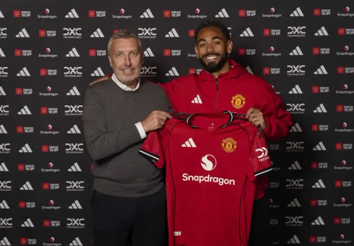 Dwóch mężczyzn prezentuje czerwoną koszulkę Manchester United. To ważny moment dla manchester united transfery.