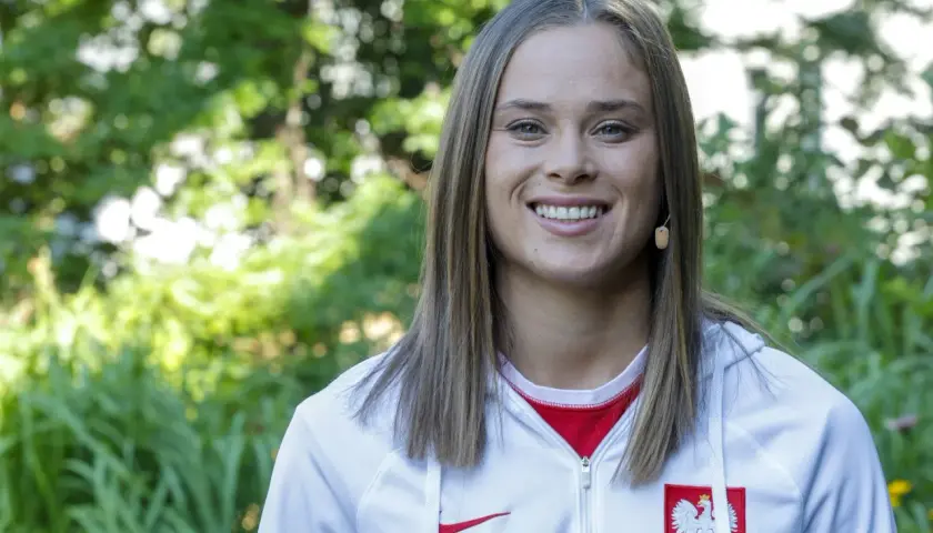 Uśmiechnięta Ewa Pajor w stroju reprezentacyjnym, symbol polskiego sportu. Jej zarobki budzą zainteresowanie, ale talent i determinacja są bezcenne.