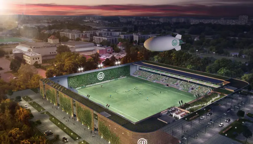 Nowoczesny stadion Warty Poznań z zielonymi fasadami i sterowcem nad boiskiem.
