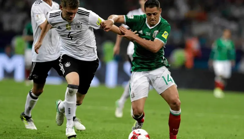 Piłkarze Niemiec i Meksyku walczą o piłkę na boisku. Intensywna gra podczas Pucharu Konfederacji UEFA.