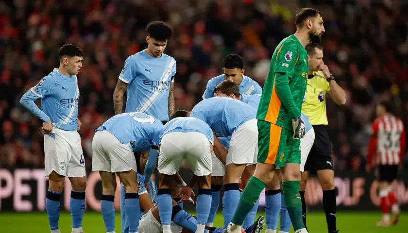 Piłkarze Manchesteru City w jasnoniebieskich strojach zbierają się w kółku na boisku. Skład drużyny w akcji.