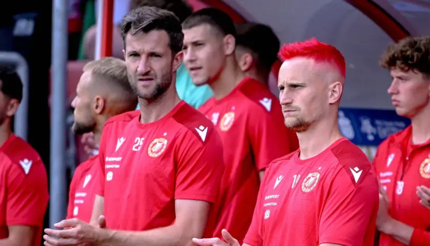 Piłkarze Widzewa Łódź w czerwonych koszulkach, jeden z nich ma jaskrawo-czerwone włosy.