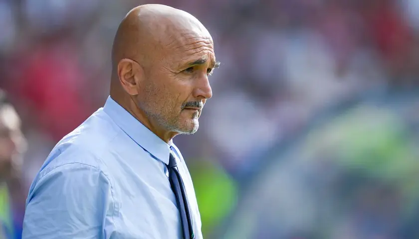 Łysy mężczyzna z wąsami, ubrany w błękitną koszulę i krawat, w skupieniu obserwuje boisko. To trener Juventusu.