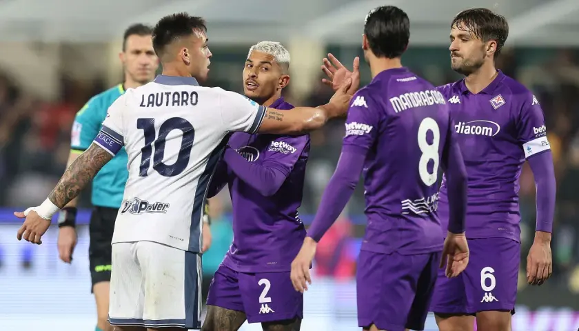 Intensywna wymiana zdań między Lautaro (Inter) a zawodnikiem Fiorentiny podczas meczu. Sędzia w pobliżu.