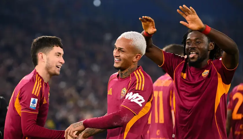 Piłkarze AS Roma świętują zwycięstwo nad Genoą CFC. Radość na twarzach zawodników, jeden z nich podnosi ręce w geście triumfu.