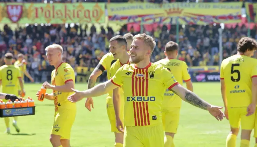Piłkarze Korony Kielce w żółtych strojach świętują po meczu z Jagiellonią Białystok. Radość na twarzach zawodników.