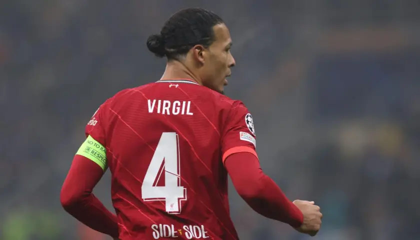 Piłkarz Virgil van Dijk w czerwonej koszulce Liverpoolu z numerem 4 i opaską "No to racism".
