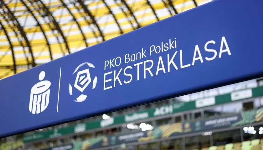 Niebieski baner z logo PKO Bank Polski Ekstraklasa na tle stadionu.